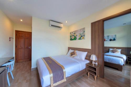 a hotel room with two beds and a desk at Maison Hai Homestay Hoi An in Hoi An