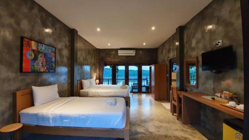 a hotel room with two beds and a television at Chiang Klong Riverside Resort in Chiang Khan