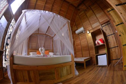 Habarana Tree House Ambasewana Resort في هارابانا: غرفة بسرير في منزل خشبي