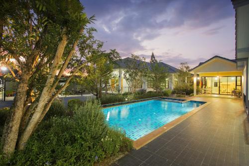 a swimming pool in front of a house at Baan Phurit Khaoyai in Pak Chong