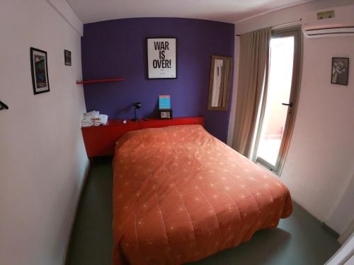 an orange bed in a room with a window at Malevo Murana Hostel in Buenos Aires