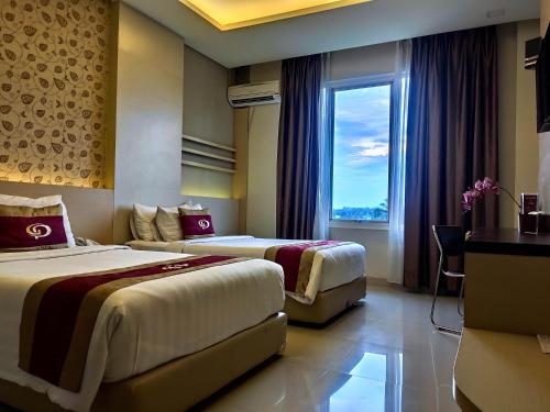 2 łóżka w pokoju hotelowym z oknem w obiekcie Grand Parama Hotel w mieście Tanjungredep