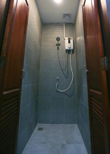 a bathroom with a shower with a hose in it at Petit Espace Boutique Hostel in Vientiane