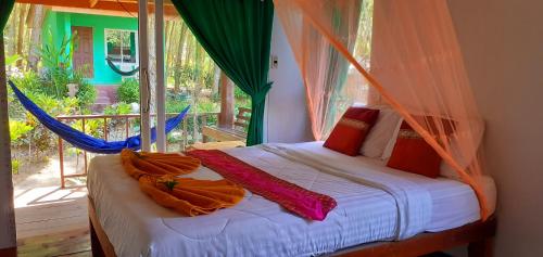 a bedroom with a bed with a hammock and a window at Lanta Maikeaw Bungalow in Ko Lanta
