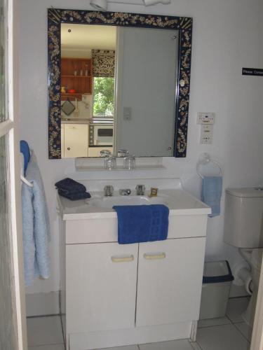 a bathroom with a white sink and a mirror at Aimeo Cottage in Russell