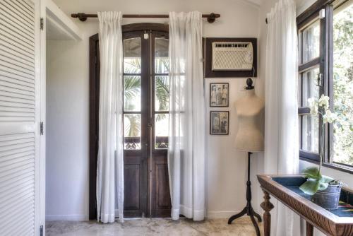 a door in a hallway with white curtains and a lamp at Villa Balthazar in Búzios