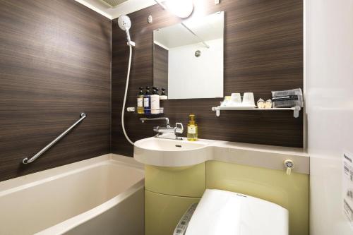 een badkamer met een wastafel, een toilet en een spiegel bij Ark Hotel Osaka Shinsaibashi -ROUTE INN HOTELS- in Osaka