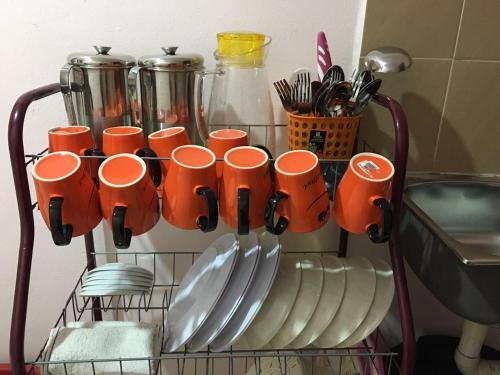 a rack with orange cups and plates and utensils at langkawi homestay murah kawasan bandar in Kuah