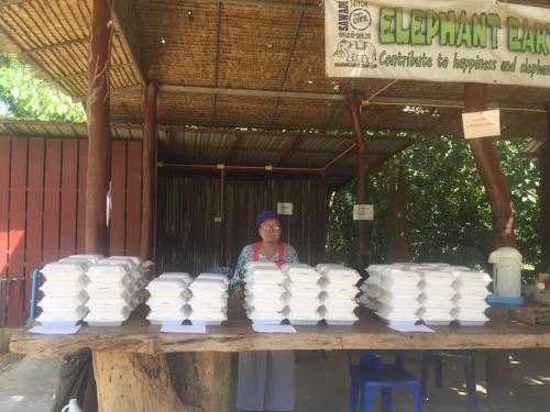 a woman standing in front of a table of white plates at Yayee Homestay in Sai Yok