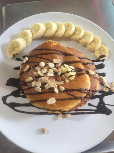 a plate with a stack of pancakes with bananas and nuts at Yayee Homestay in Sai Yok