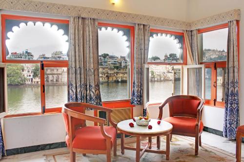a room with two chairs and a table in front of windows at Hotel Sarovar On Lake Pichola in Udaipur
