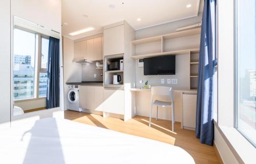 a bedroom with a bed and a kitchen with a desk at Hi Residences in Jeju