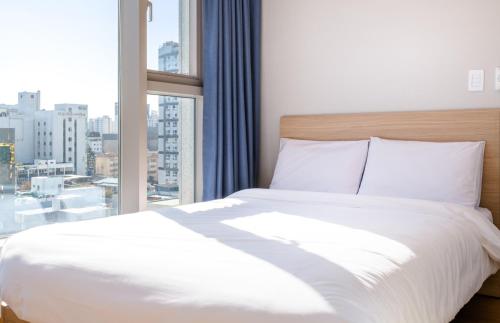 a bedroom with a white bed and a large window at Hi Residences in Jeju