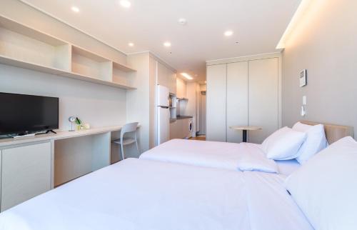 a hotel room with two beds and a tv at Hi Residences in Jeju