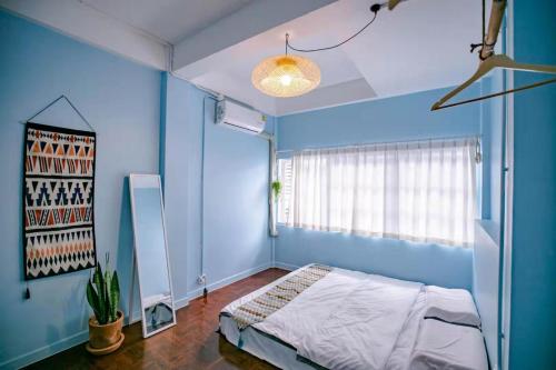 a blue bedroom with a bed and a window at Float's House in Chiang Mai