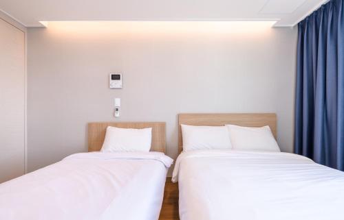 two beds in a room with blue curtains at Hi Residences in Jeju