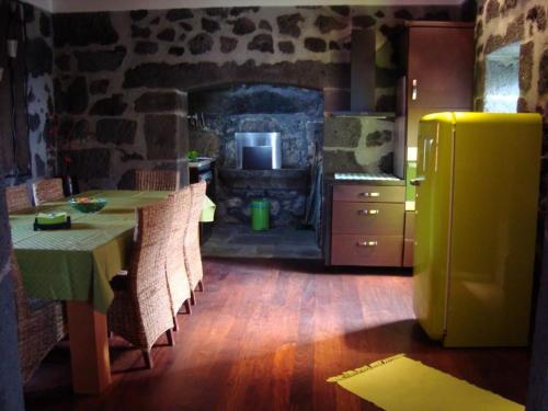 une cuisine avec une table avec des chaises et un réfrigérateur dans l'établissement Casa da Ermida, à Velas