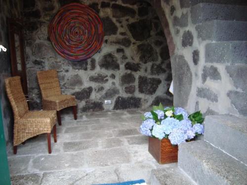 uma sala com duas cadeiras e um vaso de flores em Casa da Ermida em Velas