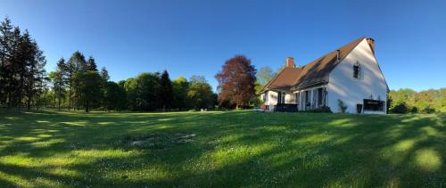 uma casa num campo relvado ao lado de um edifício em Domaine de La Charmille em Ermenonville