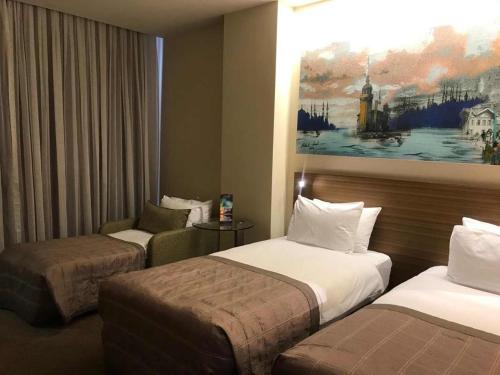 a hotel room with two beds and a chair at Gorrion Hotel Istanbul in Istanbul