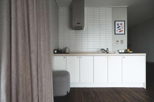 a kitchen with white cabinets and a sink at Hotel Seogwipean in Seogwipo