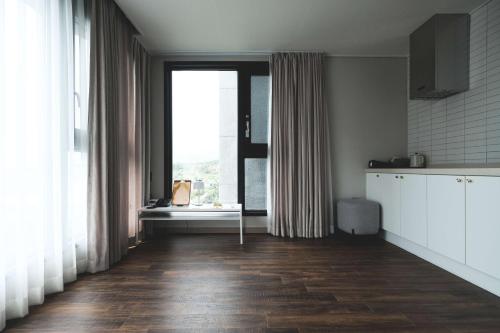 a kitchen with wooden floors and a large window at Hotel Seogwipean in Seogwipo