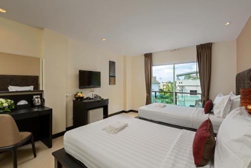 a hotel room with two beds and a television at Baramee Resortel in Patong Beach