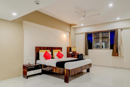 a bedroom with a bed with red pillows and a window at Dhuri Resort in Vasai
