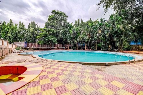 a large swimming pool in a yard with trees at Dhuri Resort in Vasai