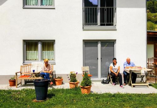 three people sitting on a patio in front of a building at Ferienhaus Gundi in Pettneu am Arlberg