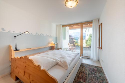 ein Schlafzimmer mit einem Holzbett und einem Fenster in der Unterkunft Casa La Prada in Flims