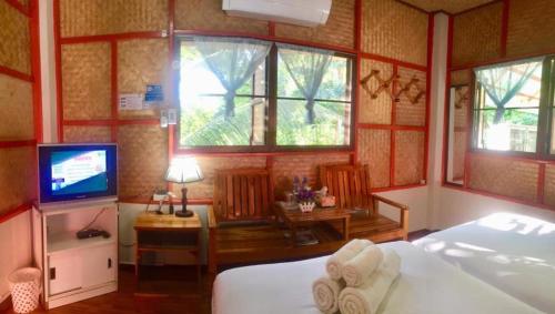 a bedroom with a bed and a tv and windows at Yayee Homestay in Sai Yok