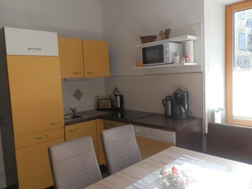 a kitchen with yellow cabinets and a table with chairs at Ferienwohnungen Trinker - Lungau Karte inklusive in Ramingstein