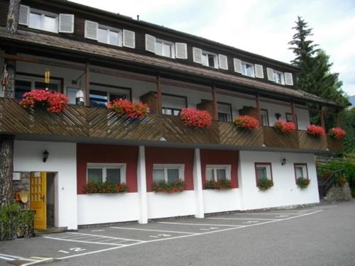 un bâtiment avec des fleurs sur ses balcons dans l'établissement Hotel Villa Emilia, à Ortisei