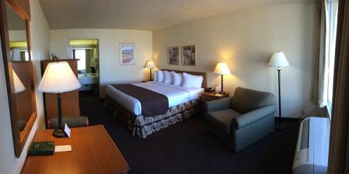 Habitación de hotel con cama y silla en Whitten Inn University, en Abilene