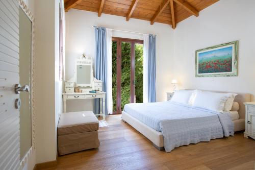 a white bedroom with a bed and a window at Arodo Seaside Villas | Villa Penelope in Sivota