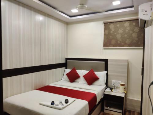 a hotel room with a bed with red pillows at Hotel Happyland in Mumbai