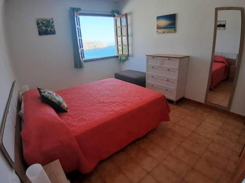 Schlafzimmer mit einem roten Bett, einer Kommode und einem Spiegel in der Unterkunft Apartment Cactus II Los Cristianos in Los Cristianos