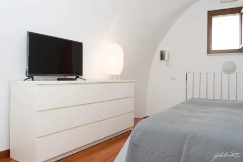 Casa Gnostra في نوتشي: غرفة نوم مع خزانة بيضاء مع تلفزيون