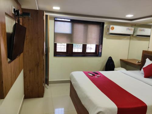 a hotel room with a bed and a window at Hotel Happyland in Mumbai