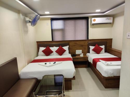 a hotel room with two beds and a couch at Hotel Happyland in Mumbai