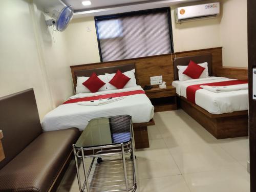a hotel room with two beds and a couch at Hotel Happyland in Mumbai