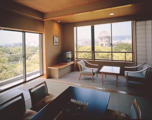 a room with a desk and chairs and a large window at Hiroshima no Yado Aioi in Hiroshima