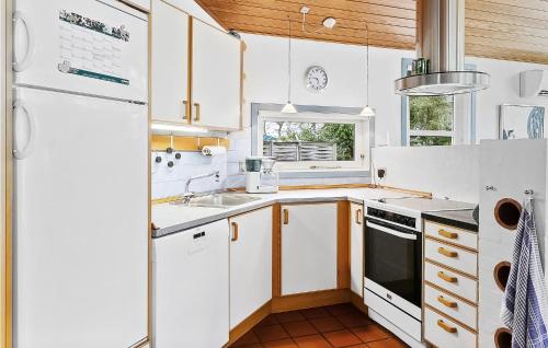 a kitchen with white cabinets and a sink and a refrigerator at Awesome Home In Gedser With Sauna in Gedser