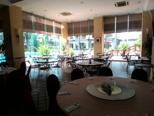 a dining room with tables and chairs and windows at Costa Mahkota (Family Homestay) @ Mahkota Melaka in Melaka