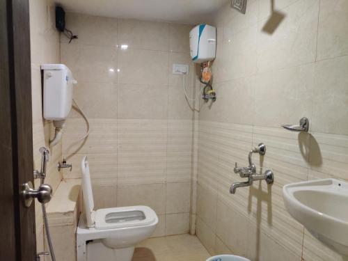 a bathroom with a toilet and a sink at Hotel Happyland in Mumbai