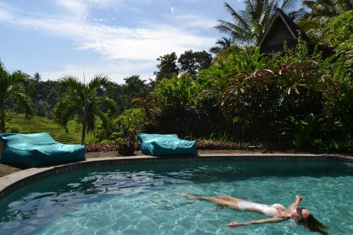 a woman laying in the water in a swimming pool at Bali Lush in Selemadeg