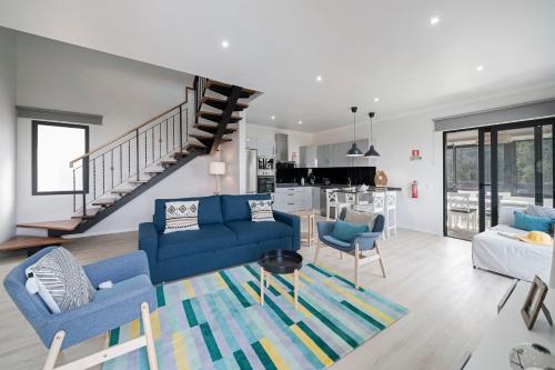 a living room with blue couches and a staircase at Vilas Felicidade Rocha by An Island Apart in Ponta do Pargo