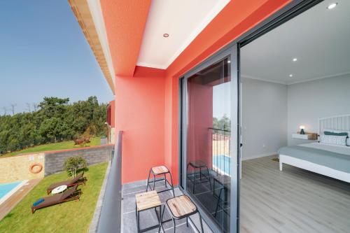a room with a balcony with a bed and chairs at Vilas Felicidade Rocha by An Island Apart in Ponta do Pargo