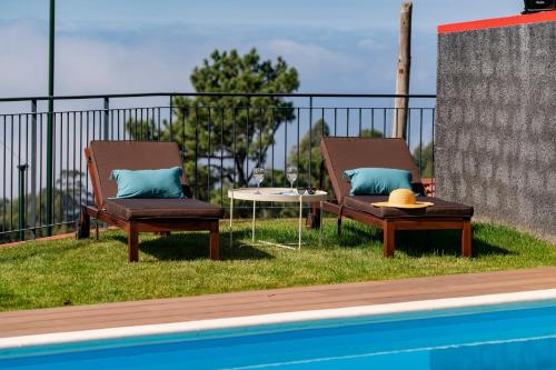 two chairs and a table next to a swimming pool at Vilas Felicidade Rocha by An Island Apart in Ponta do Pargo